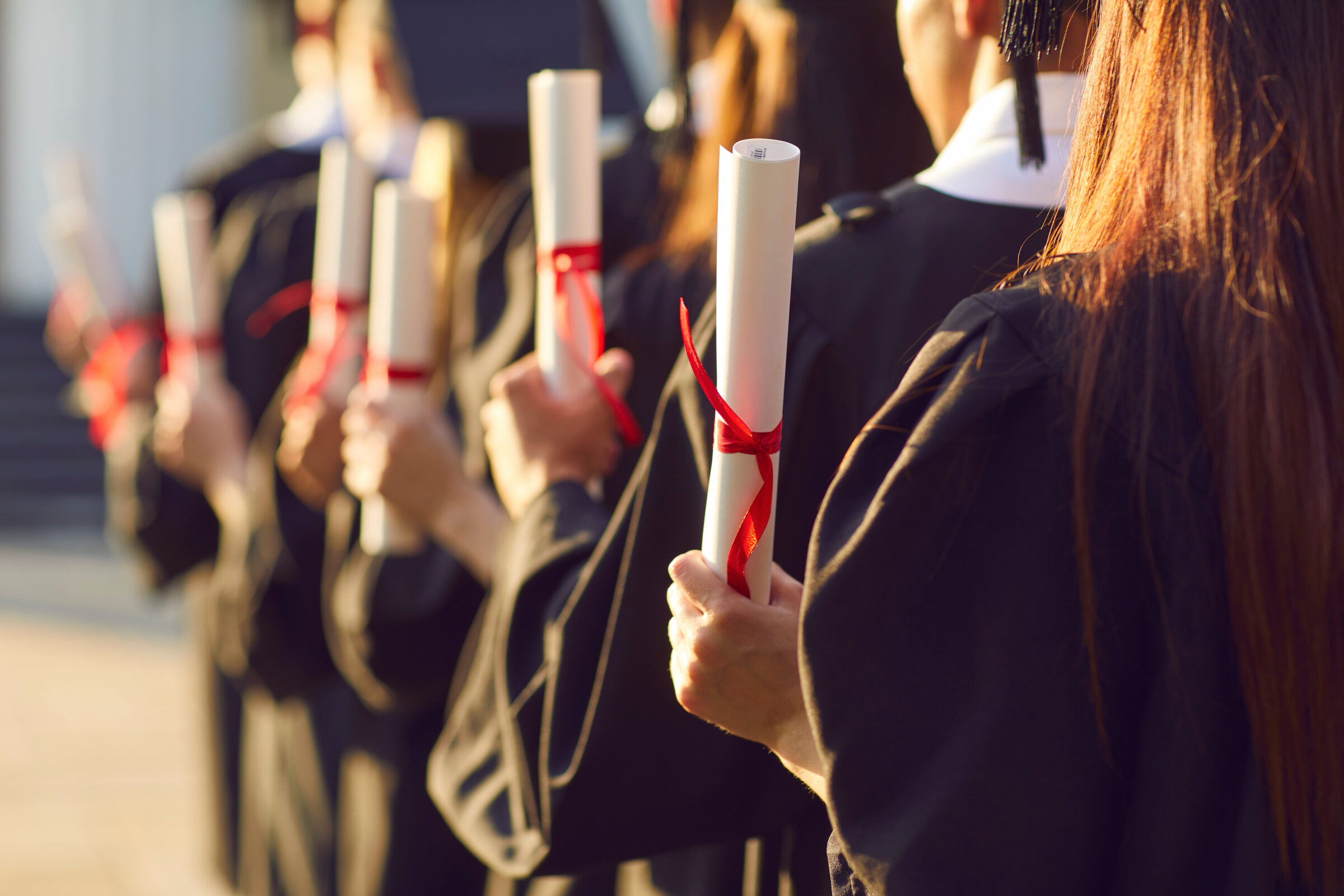 Student holding diploma degree certificate scroll at college or university graduation ceremony. High academic education accomplishment concept. Party celebration for academy graduates