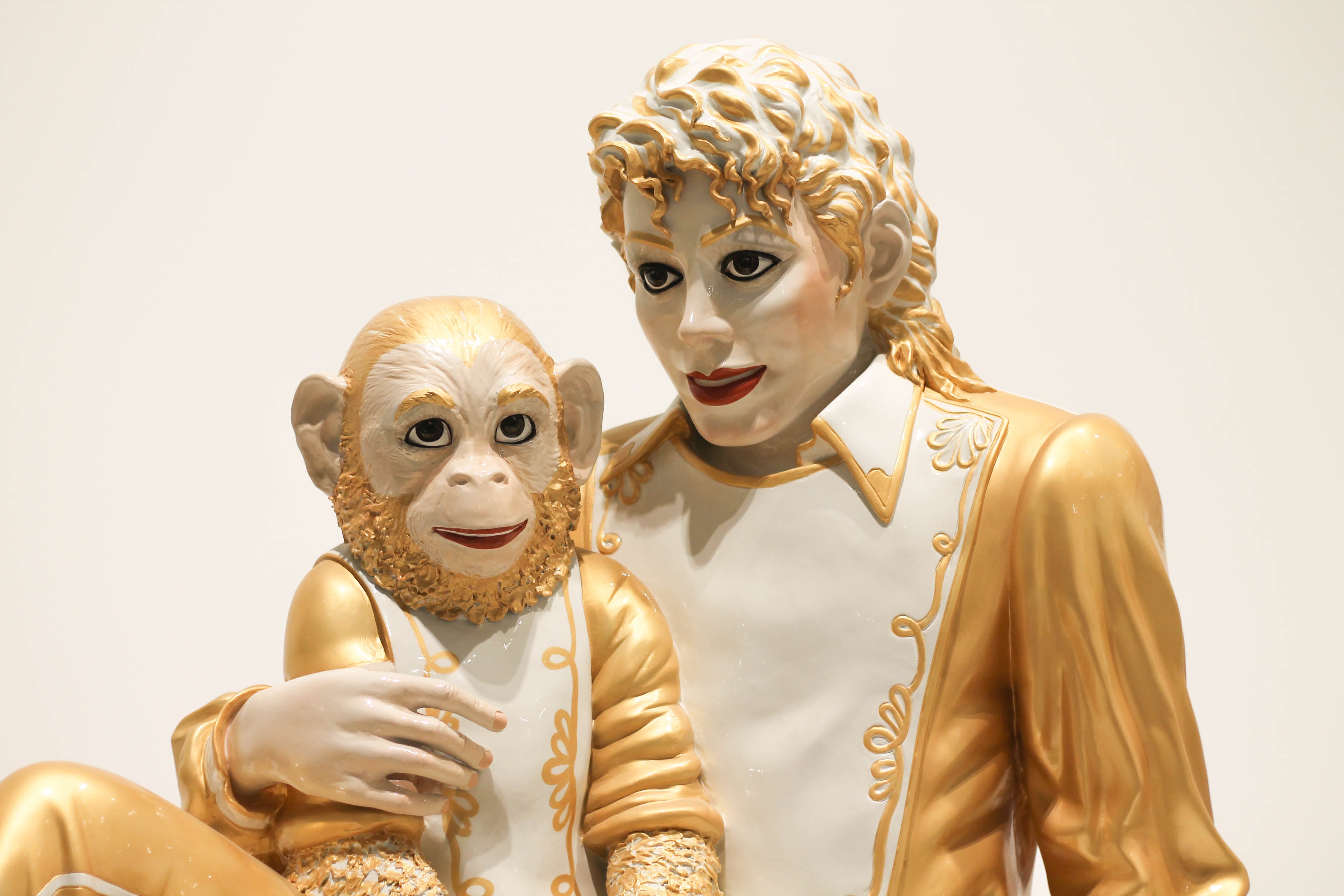 Gold and cream sculpture if a chimp and human